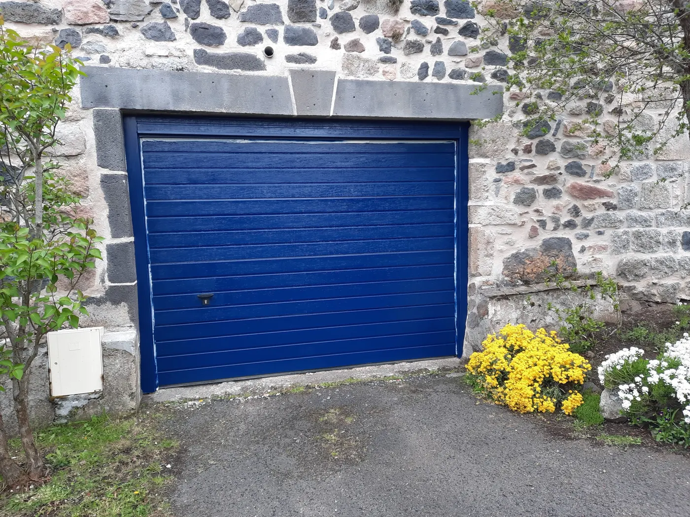 Porte de garage bleue sur un mur en pierre